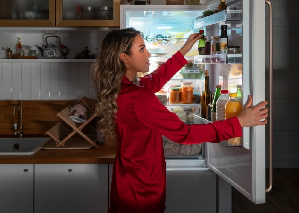 medium shot woman checking fridge night